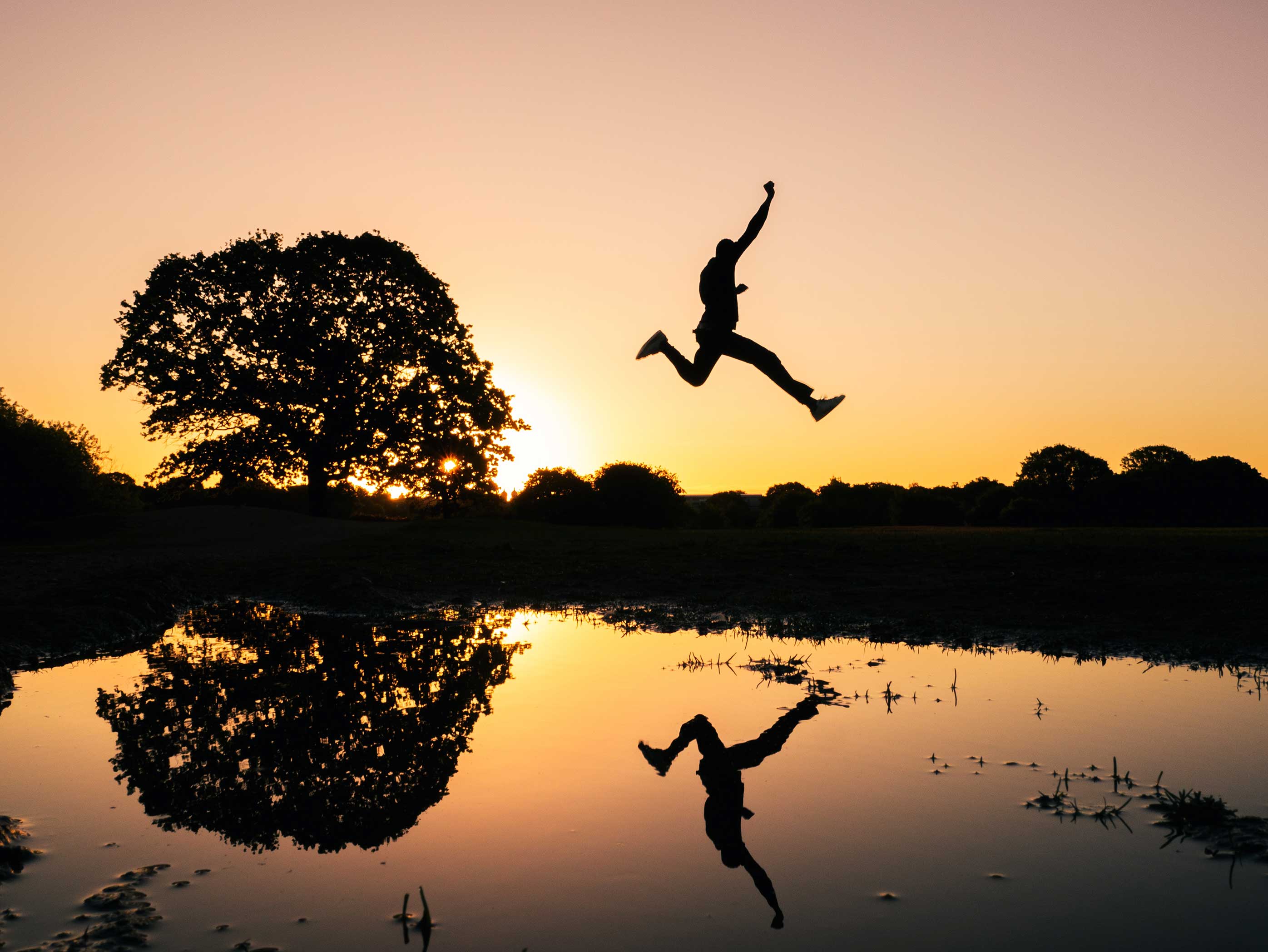 boy jumping through the lake in sunset